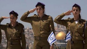 Những nữ binh Israeli đứng chào trước mộ chiến sĩ trận vong, tại một nghĩa trang quân đội trên Đồi Olive, nhìn xuống thành cổ Jerusalem. Ảnh chụp hôm 14, 4. 2013 của AP/Sebastian Scheiner