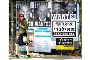 Poster truy nã Ehud Olmert (có hai poster riêng) và Ehud Barak (cả hai đều từng là cựu Thủ tướng Israel) tại Jerusalem, tháng Tư 2010. Olmert và Barak bị cáo buộc ăn hối lộ và tham nhũng. Theo Văn phòng Tổng chưởng lý Israel, trong thời gian trước khi được bầu làm Thủ tướng Israel năm 2006, ông Olmert nhận hàng trăm nghìn USD bất hợp pháp của doanh nhân người Mỹ gốc Do Thái Morris Talansky